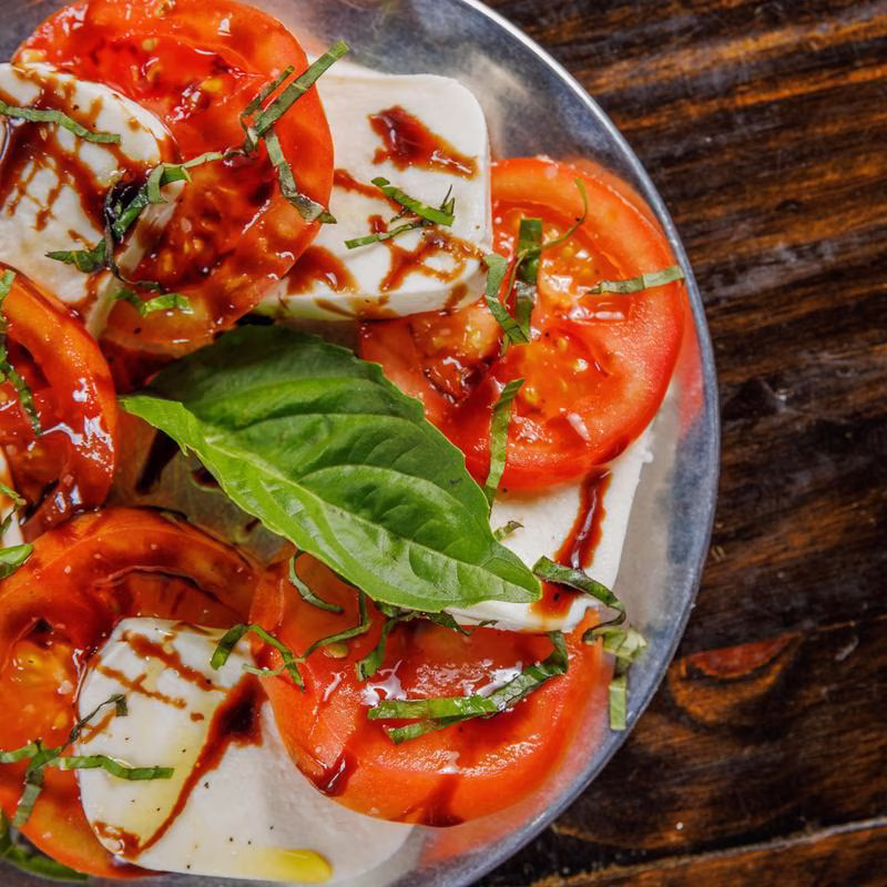 Caprese salad with tomatoes, mozzarella, basil, and balsamic glaze.