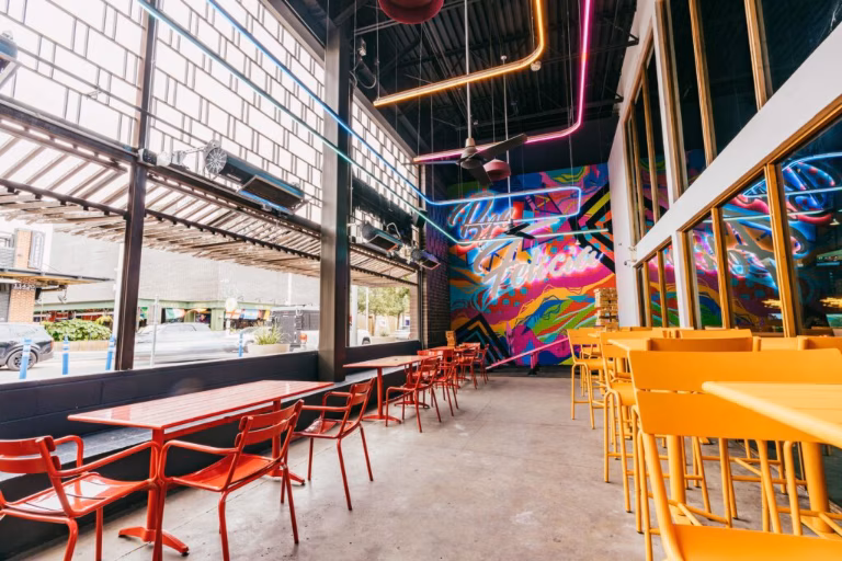 Colorful dining room with abstract mural, neon lights, red and yellow seating.