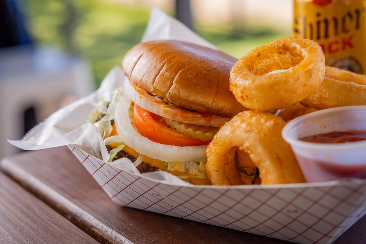 Hamburger, onion rings, and sauce in a paper tray.