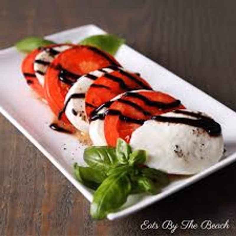 Caprese salad with sliced tomatoes, mozzarella, balsamic glaze, and basil.