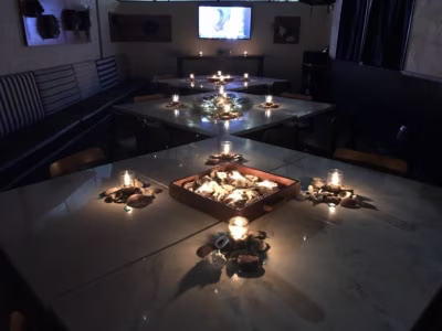 Dimly lit room with multiple tables, candles, and stone decorations.