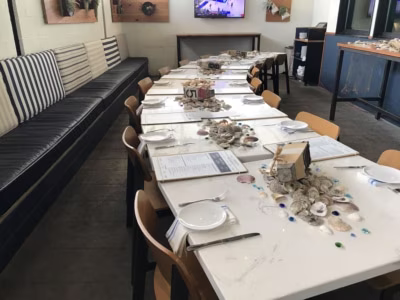 Empty restaurant dining table set with oyster shells and menus.