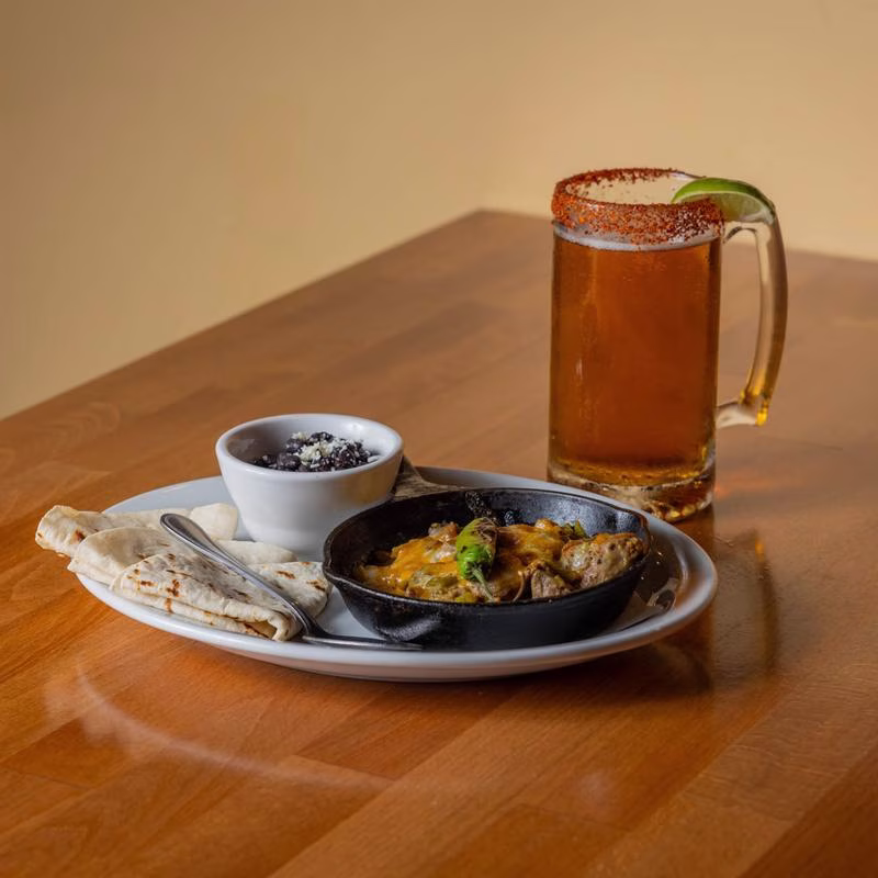 Cheesy meat skillet, black beans, tortillas, and a spiced beer mug.