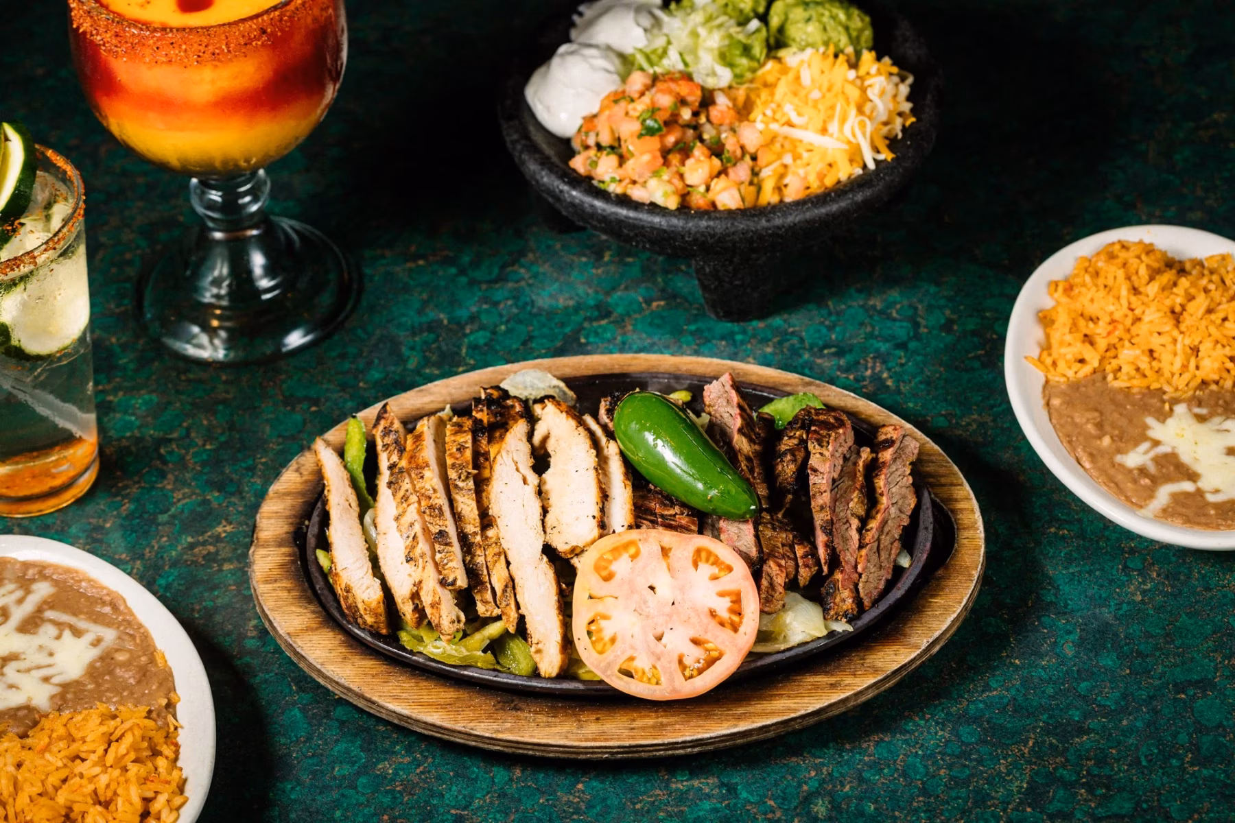 Chicken and steak fajitas, rice, beans, toppings, and two drinks.