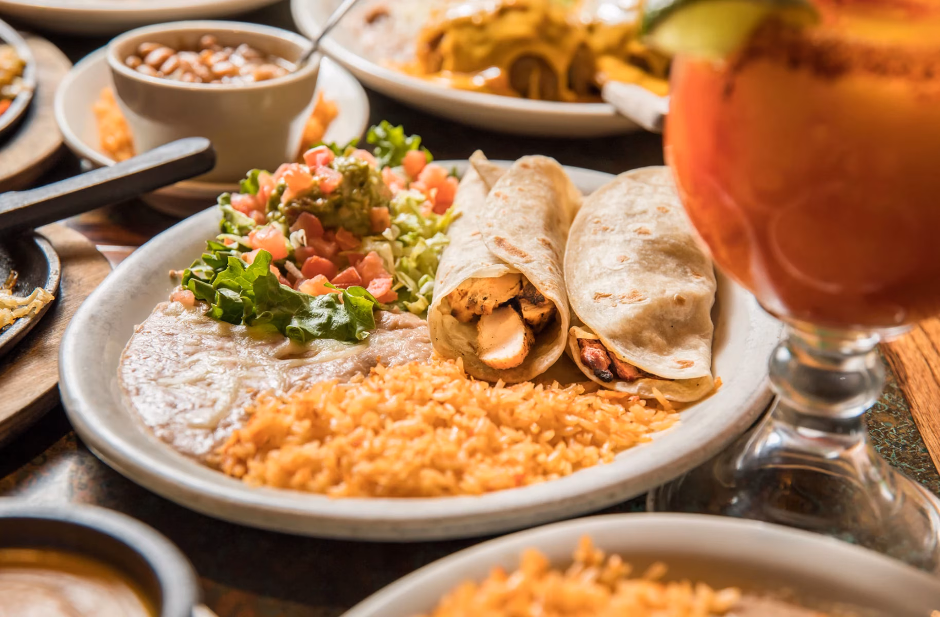 Chicken tacos, refried beans, rice, pico de gallo, and a drink.