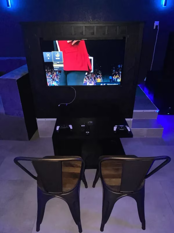 A console gaming setup with screen, two controllers, and two chairs.
