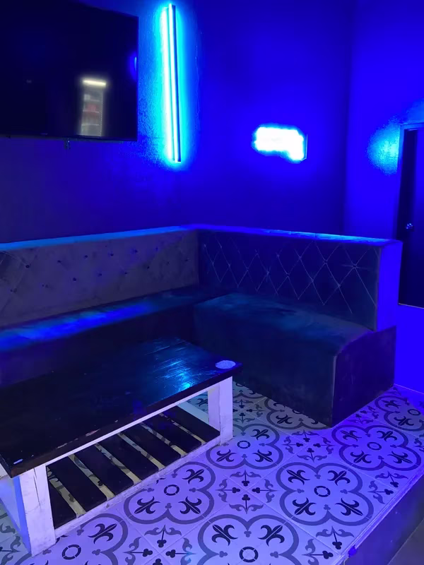 Dark blue room with booth seating, coffee table, and patterned floor.