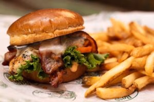 Chicken sandwich with bacon, cheese, lettuce, and a side of fries.