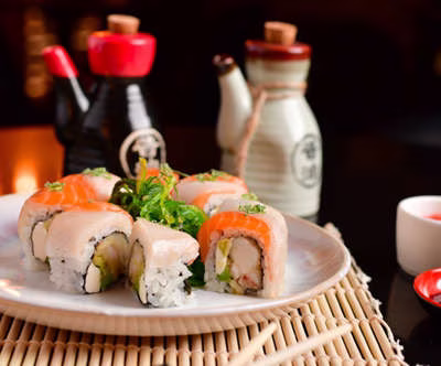 Sushi rolls topped with fish and seaweed salad on a plate.