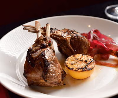 Lamb chops with grilled lemon and pickled red onions.