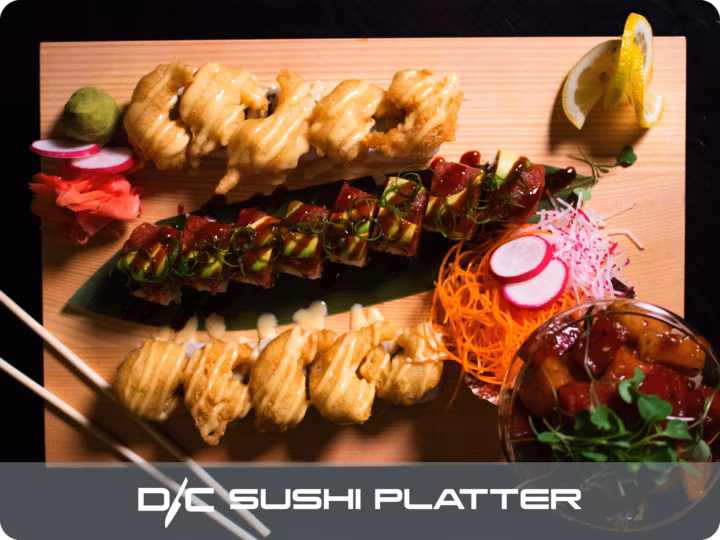 Assorted sushi rolls, poke bowl, and condiments on a wooden platter.