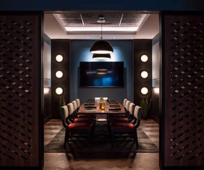 Private dining room with a long table, chairs, and large screen.