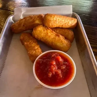 Six golden-brown fried mozzarella sticks with marinara on a tray.