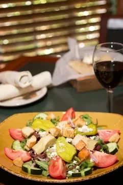 Colorful salad with various vegetables and cheese on a yellow plate.