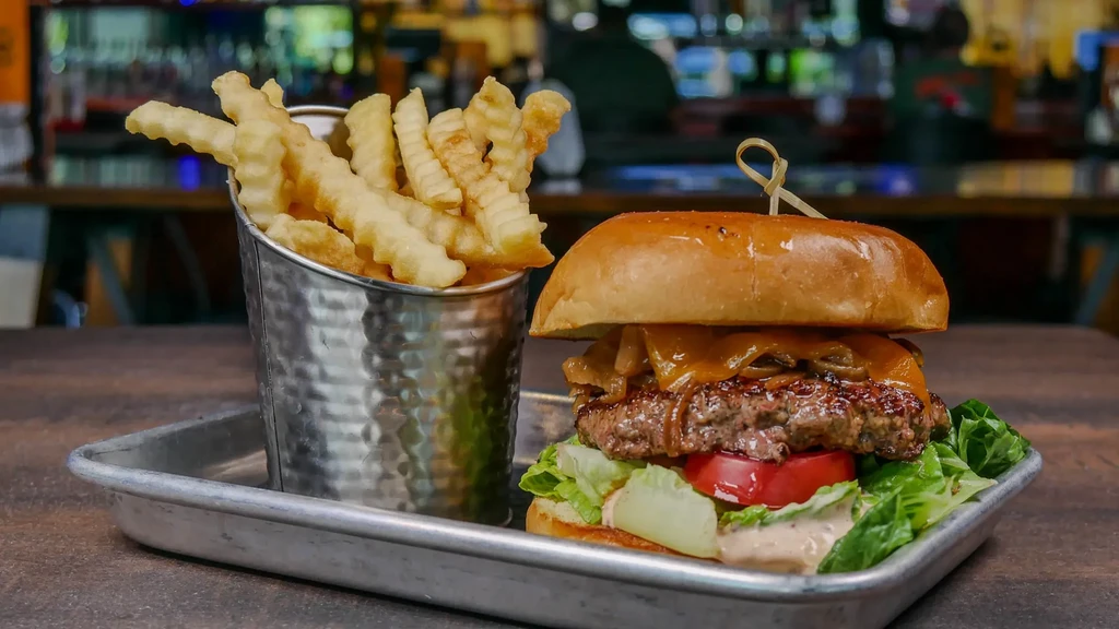 Gourmet burger with melted cheese, lettuce, tomato, and crinkle-cut fries.