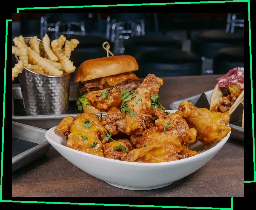 Vibrant spread of chicken, fries, burger, and taco on a dark table.