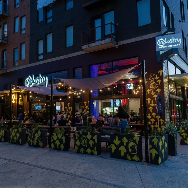 Industry restaurant patio at night with patrons under string lights.