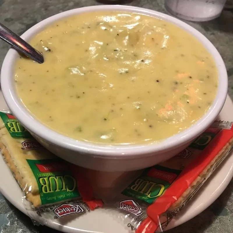 Close-up of creamy green soup, spoon, and Keebler Club crackers.