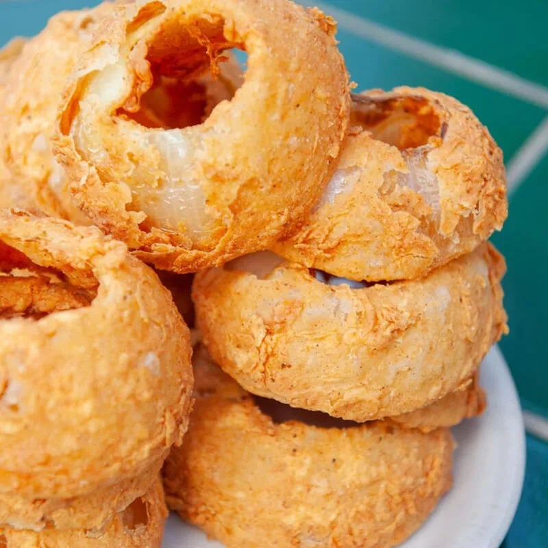 Crispy, golden-brown onion rings piled high on a white plate.
