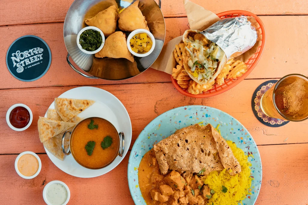 Overhead view of diverse dishes and drinks on a rustic wooden table.
