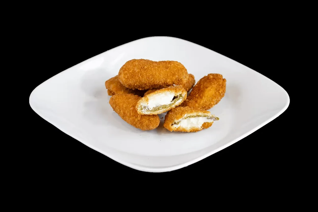 Fried jalapeño poppers with creamy cheese filling on a white plate.