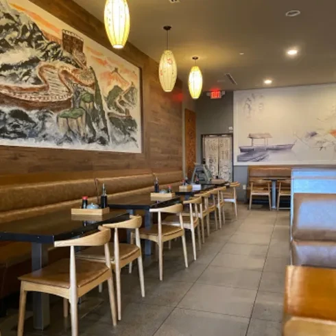 Asian restaurant interior with Great Wall mural and pendant lights.