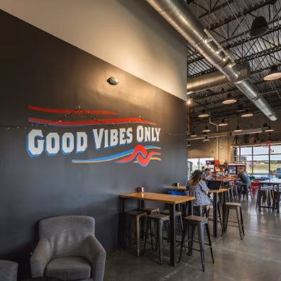 Spacious industrial-style interior with "Good Vibes Only" wall graphic and seating.