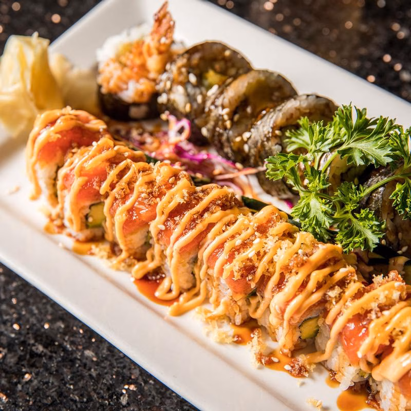 Assorted sushi platter with tuna rolls, maki, shrimp, and ginger.
