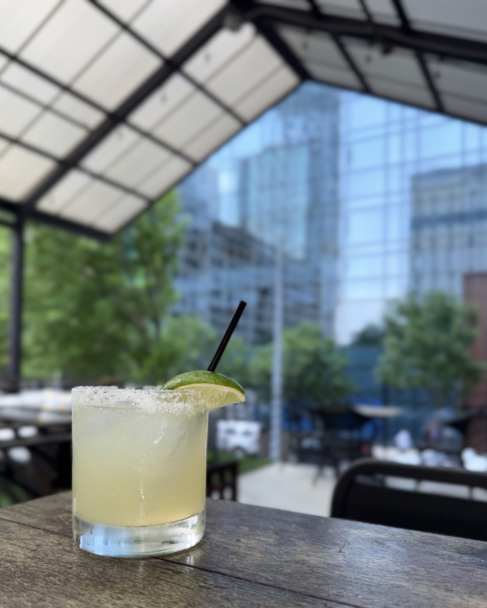 Margarita with lime and salted rim on an outdoor wooden table.