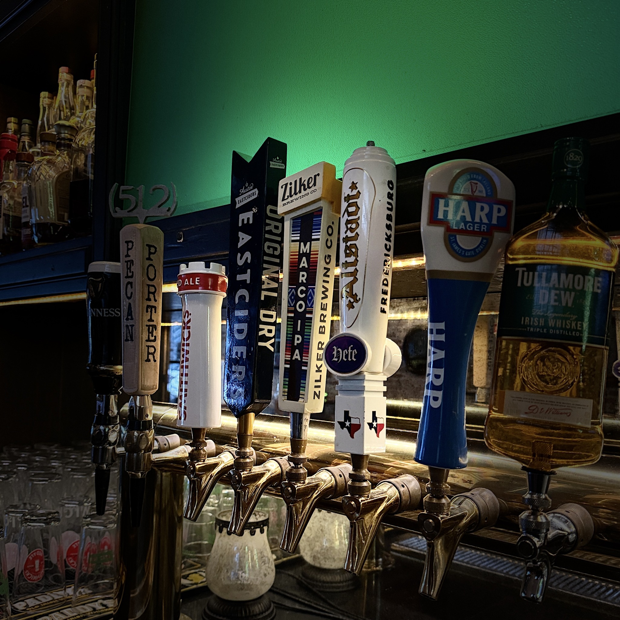 Close-up of beer tap handles and Tullamore Dew whiskey bottle on bar.