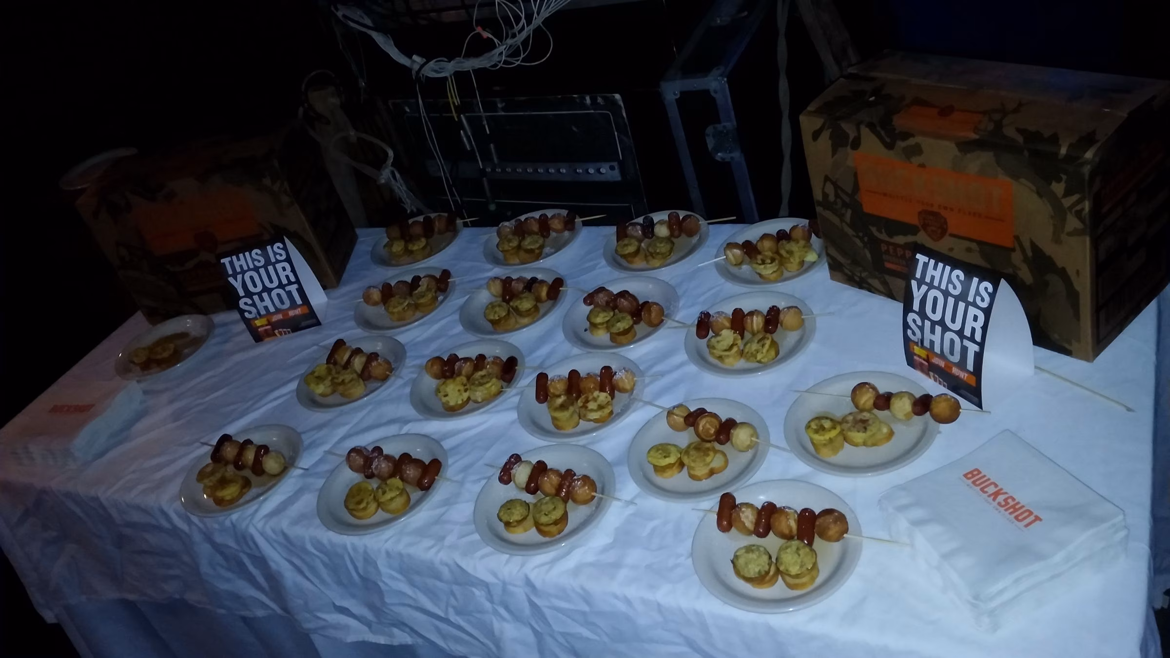 Numerous small plates of mini sausage and pastry skewers.