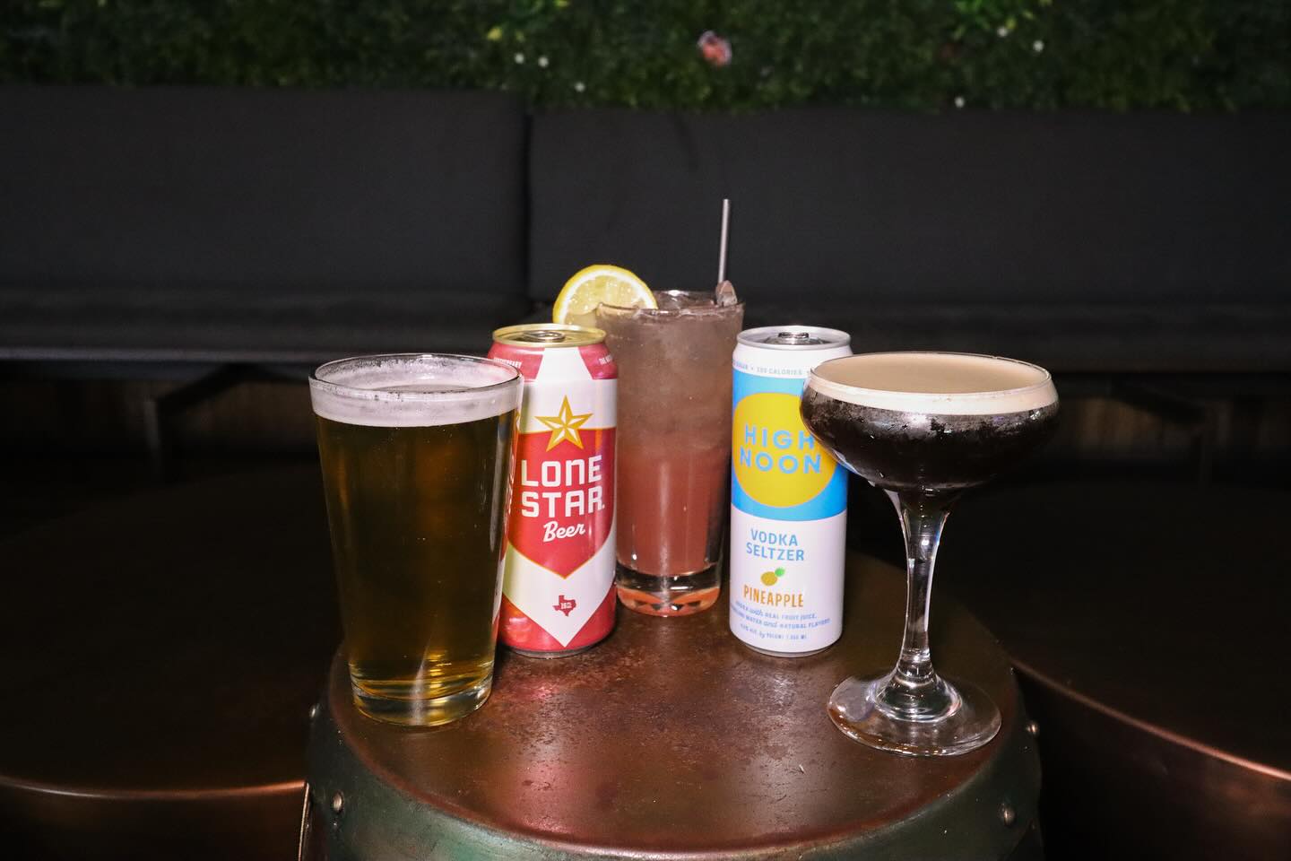 Lone Star beer, High Noon seltzer, and two cocktails on a table.