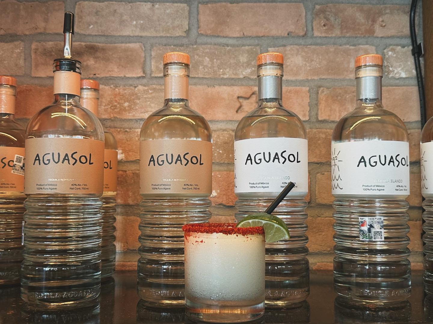 AGUASOL tequila bottles and a chili-rimmed margarita on a bar.