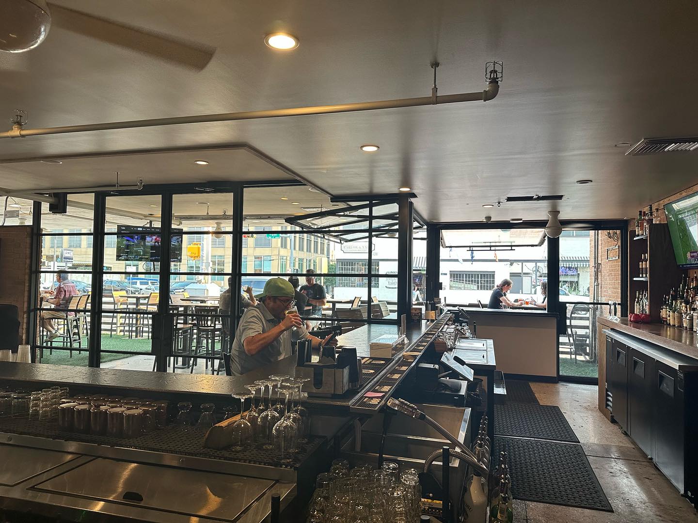 People enjoying drinks at a bar with indoor and outdoor seating.