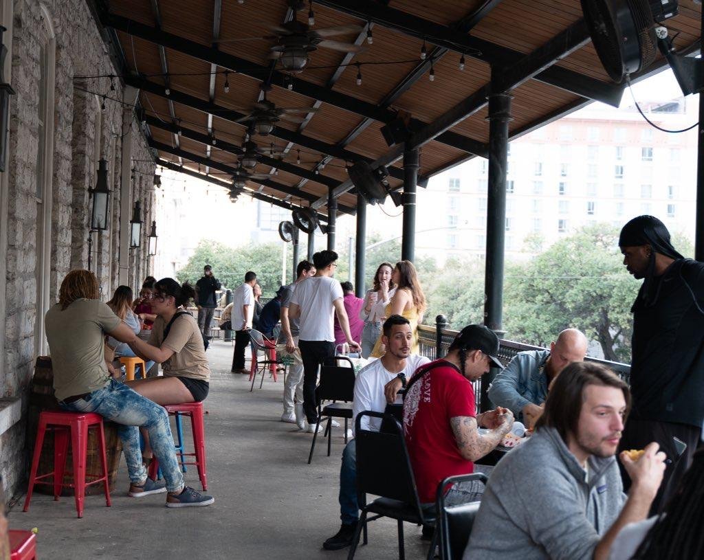 People socializing and eating on a covered outdoor restaurant patio.