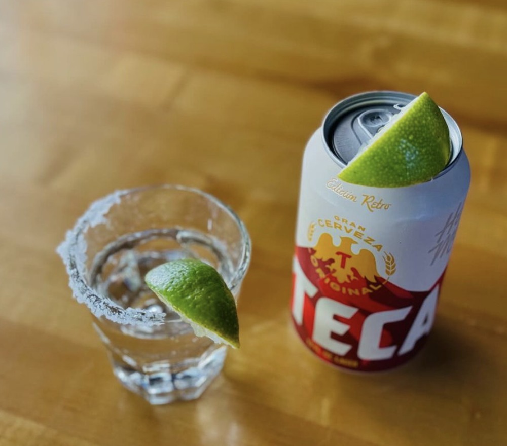 Salt-rimmed glass with lime wedge, next to Tecate beer can with lime.
