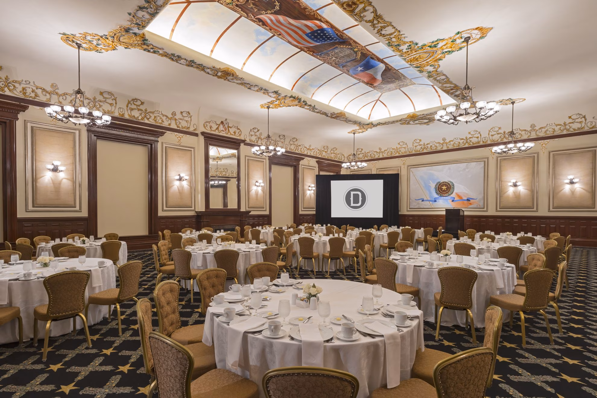 Grand ballroom with set round tables, chairs, and decorative ceiling art.