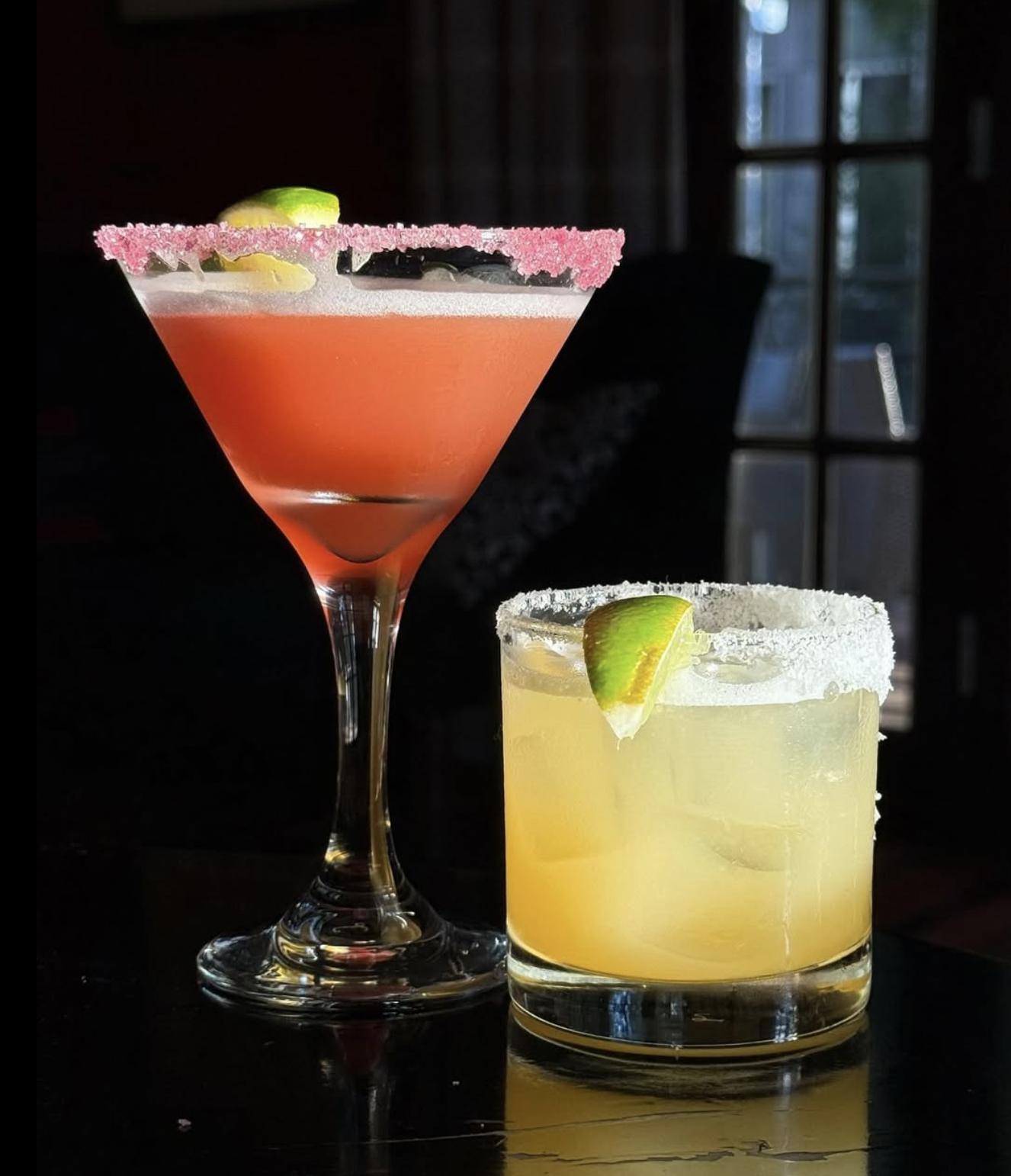 Pink drink in martini glass, yellow drink in rocks glass.