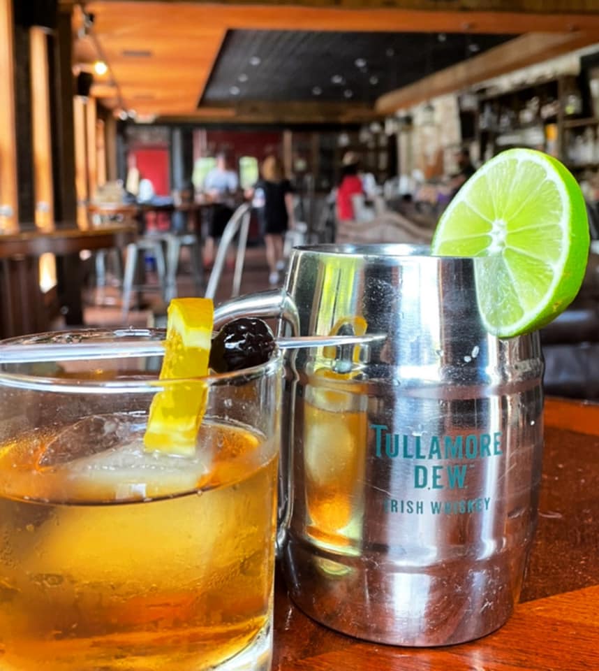 Two drinks: one garnished with orange, one Tullamore Dew mug with lime.