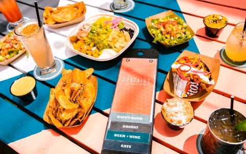 Colorful table with cocktails, chips, and various small meals from 'Upstairs'.