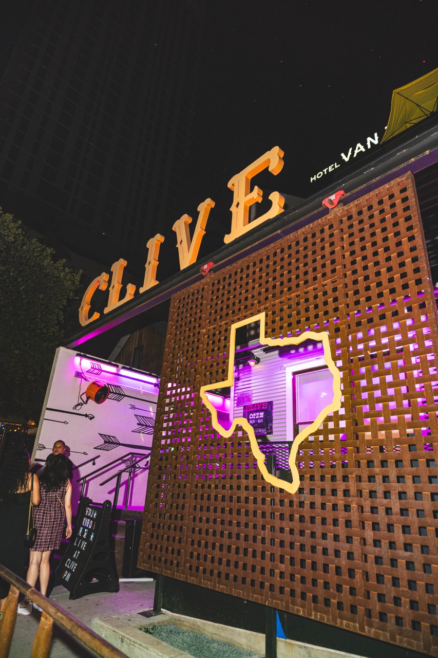 CLIVE sign and Texas-shaped cutout glowing purple at night.