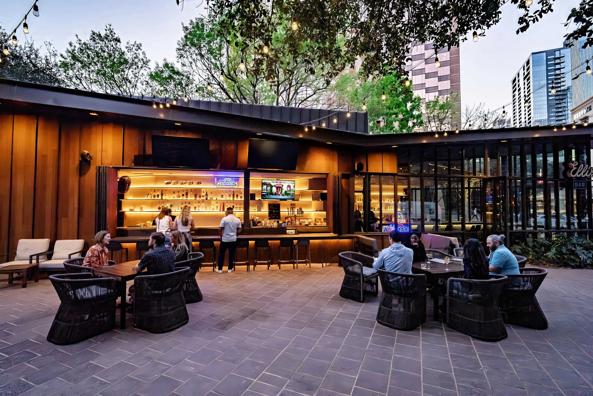 Outdoor bar patio at twilight with people and string lights.