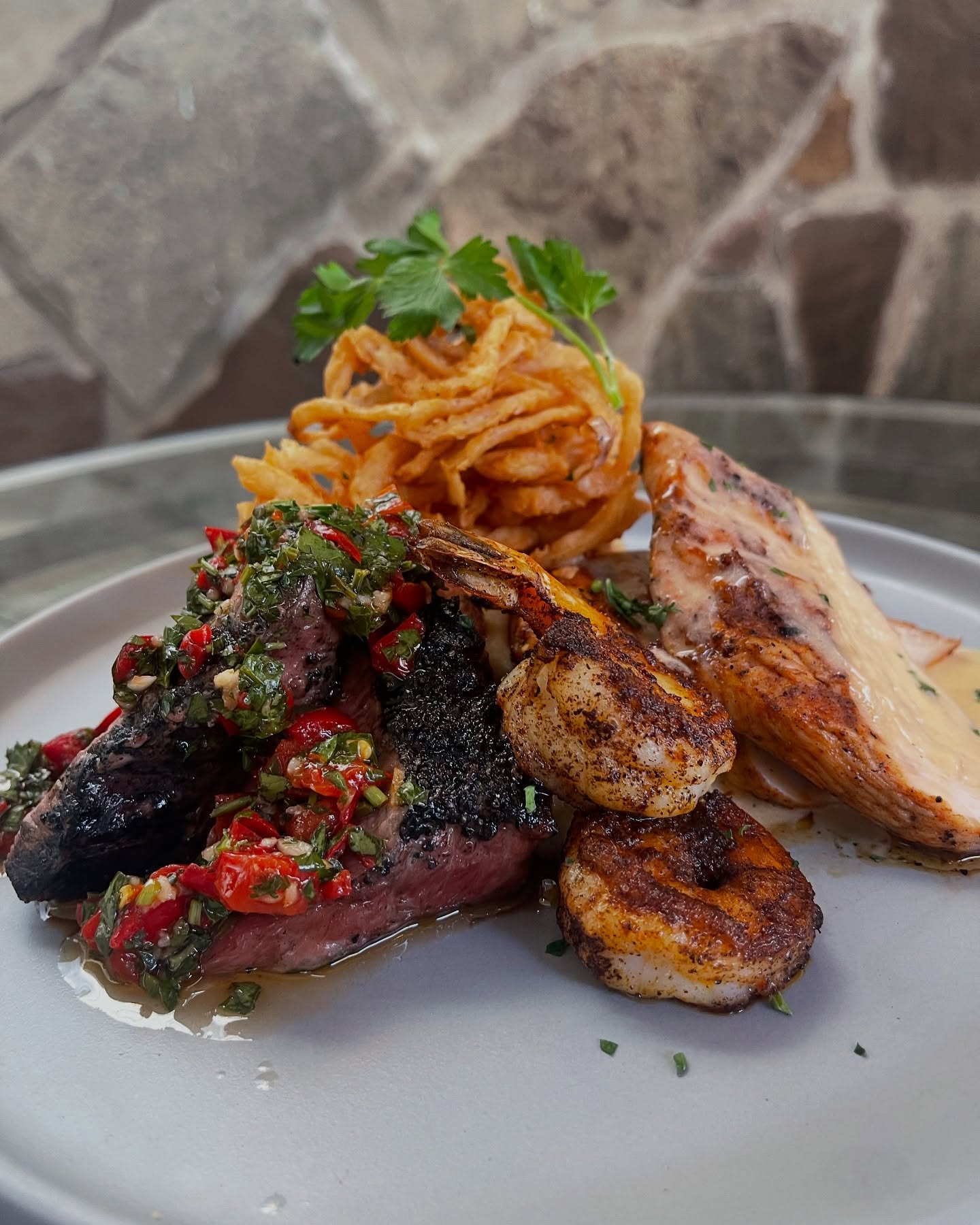 Steak with relish, seasoned shrimp, chicken, and fried onion straws.