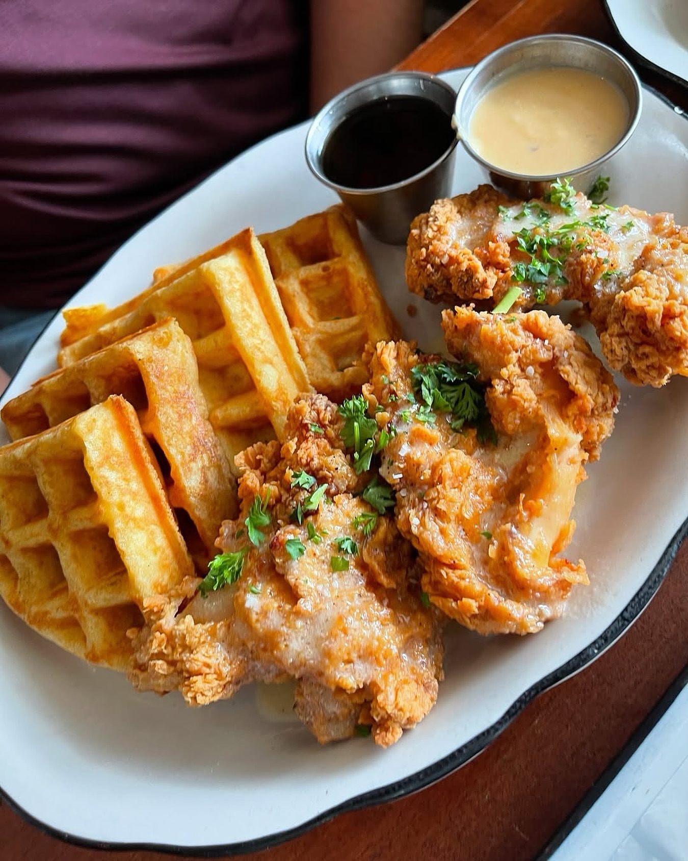 Fried chicken and waffles with two dipping sauces on a plate.