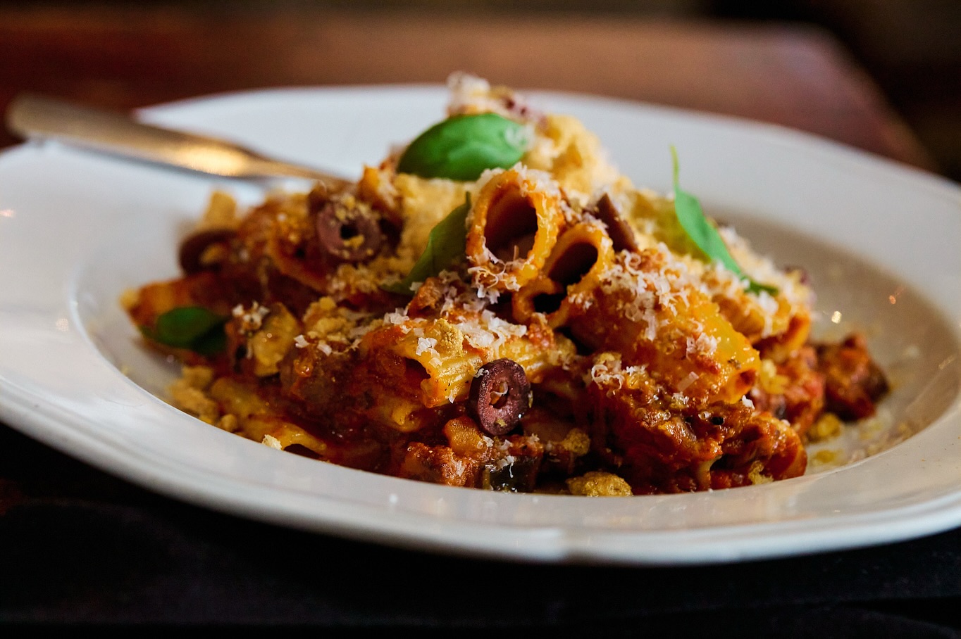 Pasta with tomato sauce, olives, grated cheese, and basil.