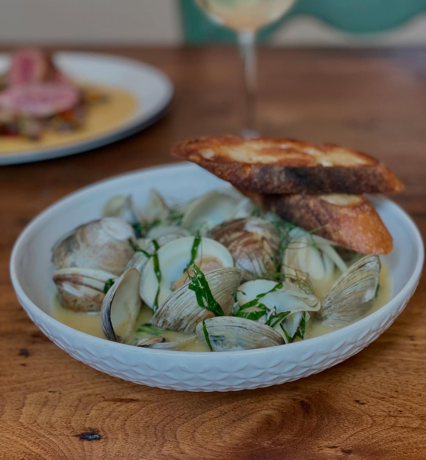 Clams in broth with herbs and toasted baguette slices.