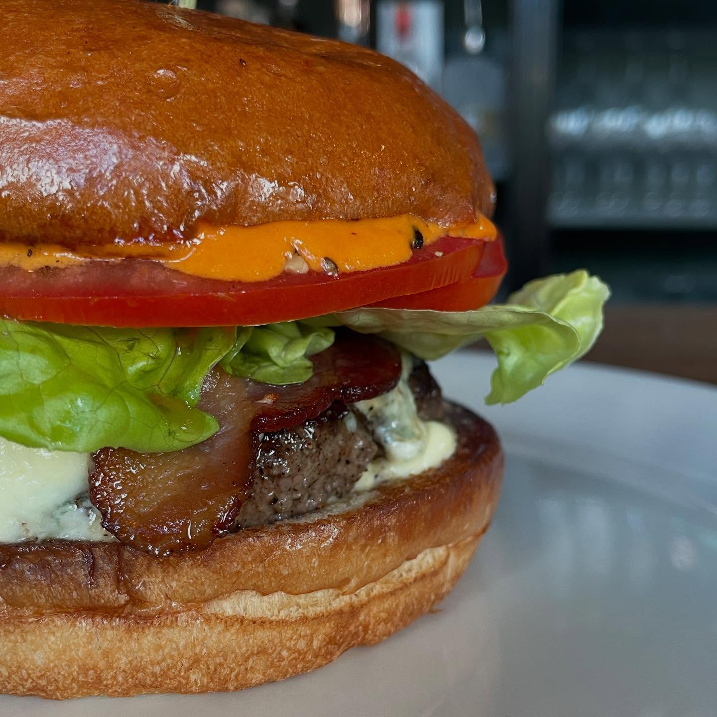 Close-up of a bacon blue cheese burger with lettuce and tomato.