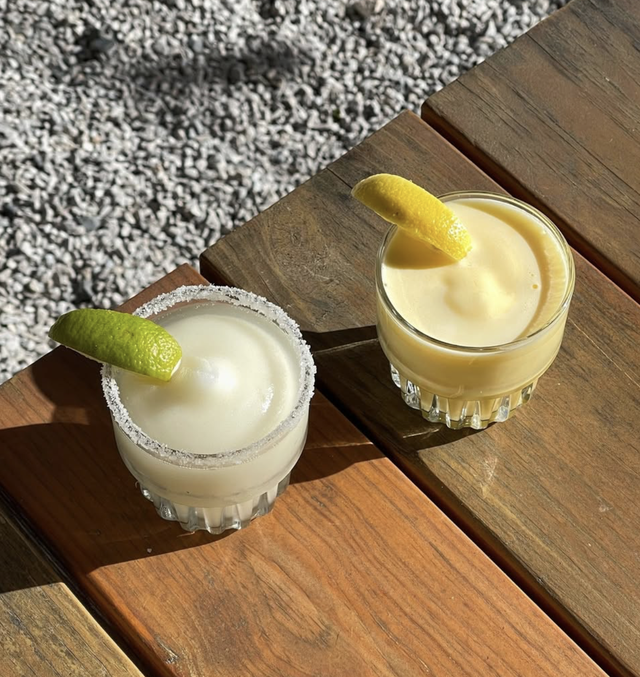 Two frozen drinks, one with lime and salt, one with lemon.