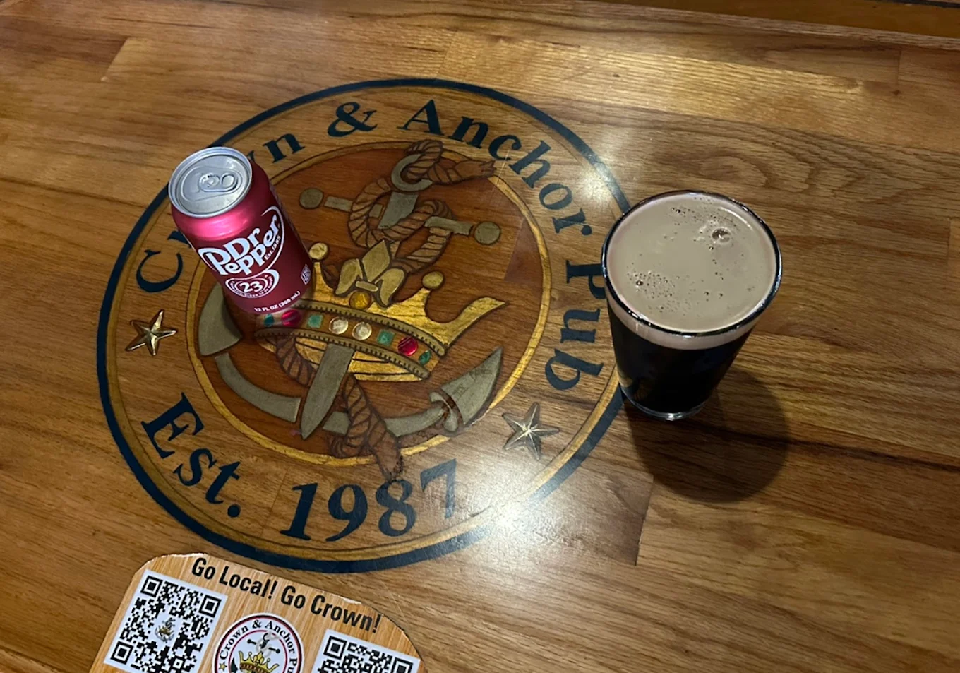 Red Dr. Pepper can and dark beverage on Crown & Anchor table.