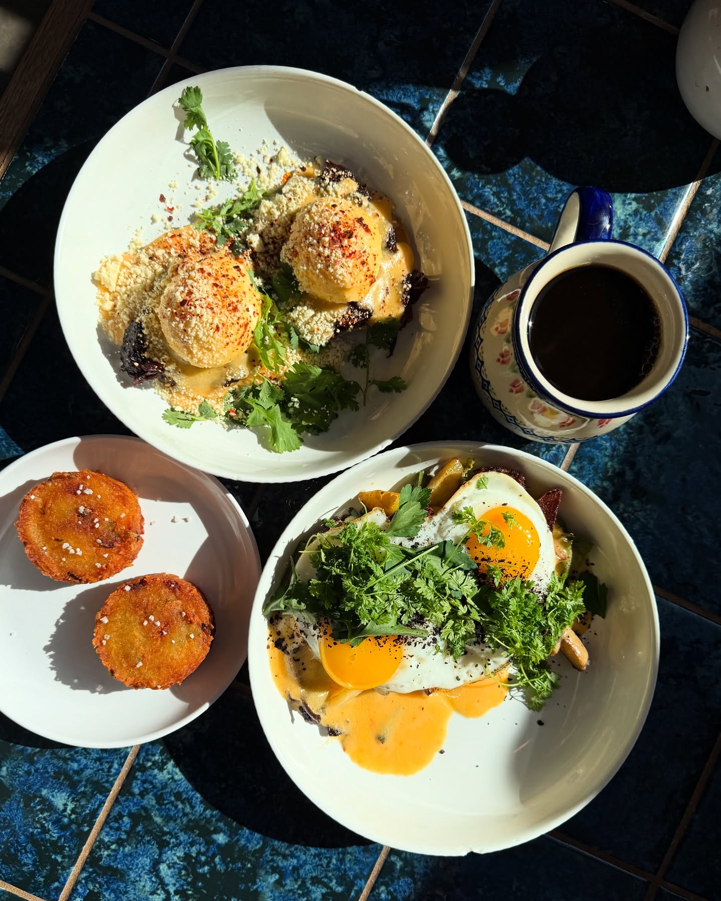 Overhead shot of egg dishes, fried patties, and a coffee mug.